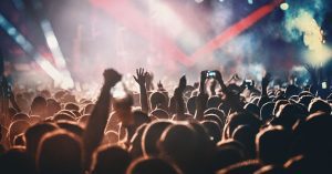 Concertgoers with arms in the air enjoying light show